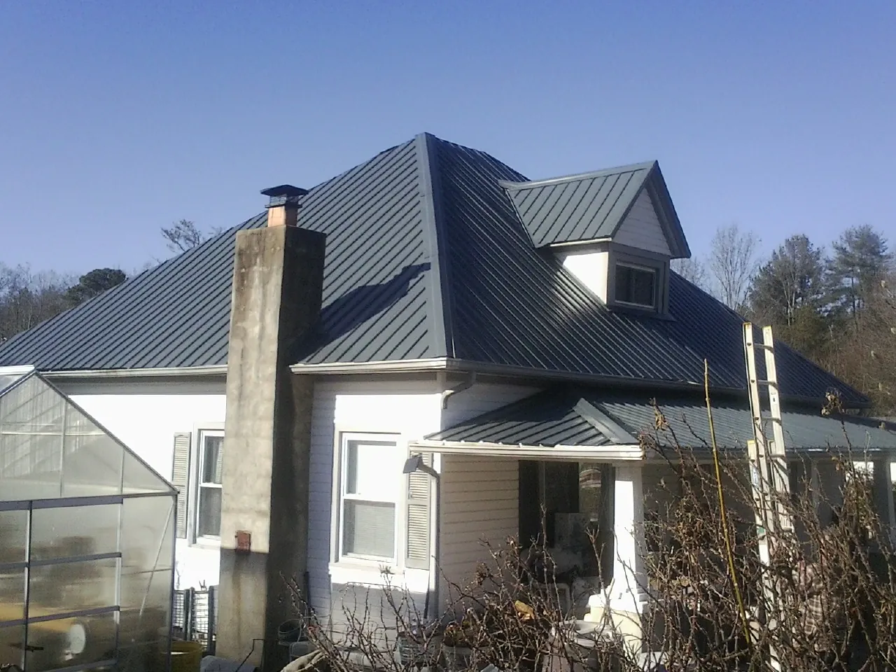 Dark blue standing seam metal roof on a white farmhouse with dormer — Slate & Tile Roof Repair by Roofing Brothers in Pontotoc