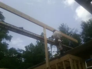 Carpenter setting a ridge beam over a new addition frame — Ice Dam Removal by Roofing Brothers in Pontotoc