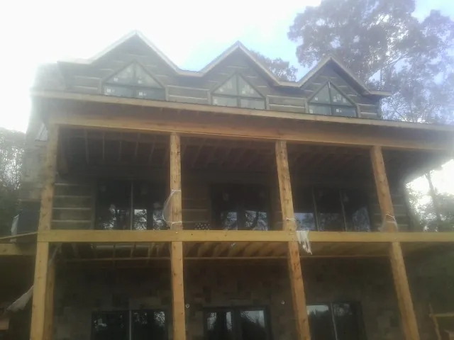 Dormers and porch framing on a large log home under construction — Roof Coating work by our crew in Pontotoc