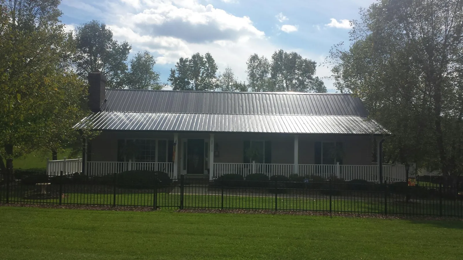 Gray metal roof on a brick ranch with a full width front porch — Gutter Guard Installation work by our crew in Pontotoc