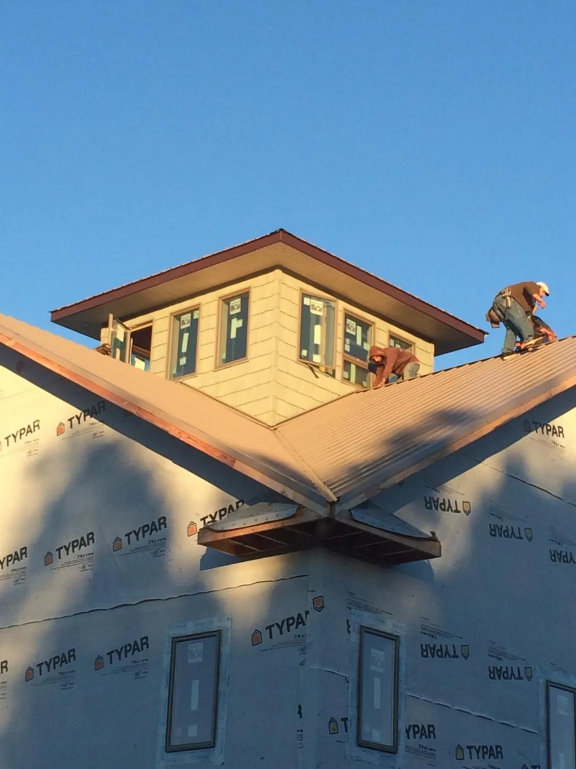 Roofers working around a rooftop cupola on a new metal roof at sunset — Roof Waterproofing in Pontotoc by Roofing Brothers